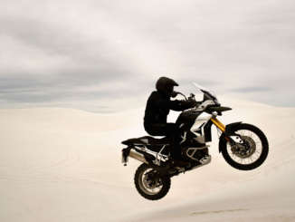 The view from the cockpit of a motorcycle. A cell phone mounted to the bars shows an incoming call.