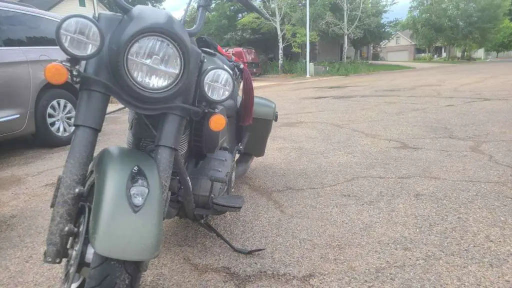 A frontal view of a very dirty 2020 Indian Springfield Dark Horse parked in a neighborhood on a rainy day.